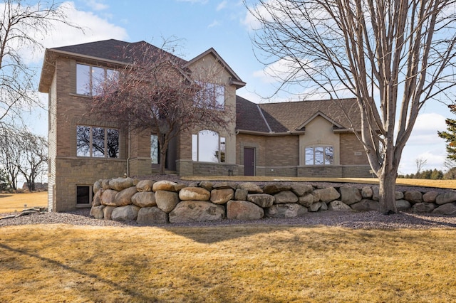 view of front facade featuring brick siding, a front lawn, and a shingled roof