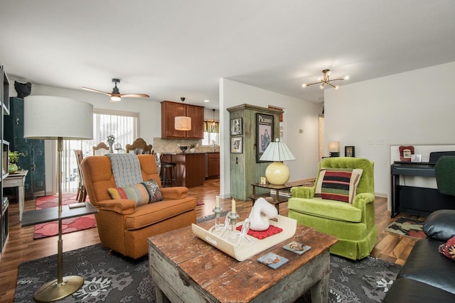 living room featuring sink, dark hardwood / wood-style flooring, and ceiling fan with notable chandelier