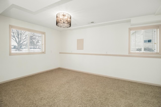 carpeted spare room featuring an inviting chandelier