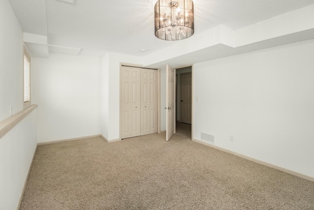 carpeted empty room featuring a notable chandelier