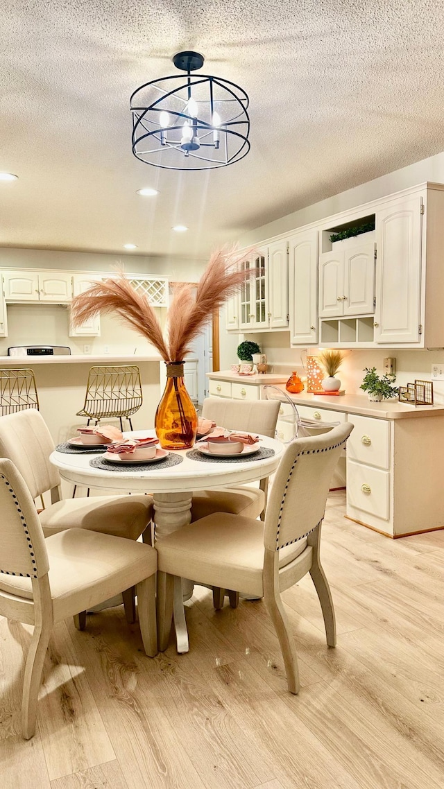 dining space with a textured ceiling and light wood-type flooring