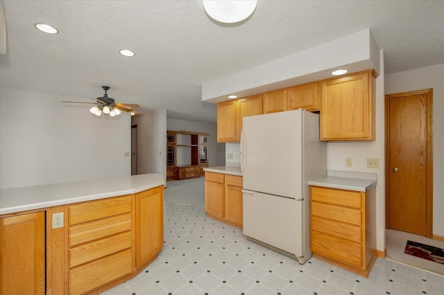 kitchen with white fridge, light brown cabinetry, a textured ceiling, and ceiling fan