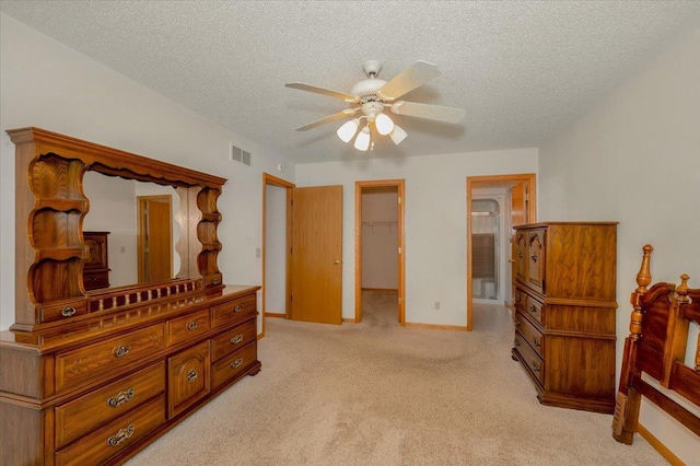 carpeted bedroom featuring a textured ceiling, ceiling fan, a spacious closet, and a closet