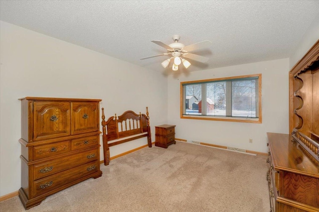 bedroom featuring ceiling fan, light carpet, and a textured ceiling