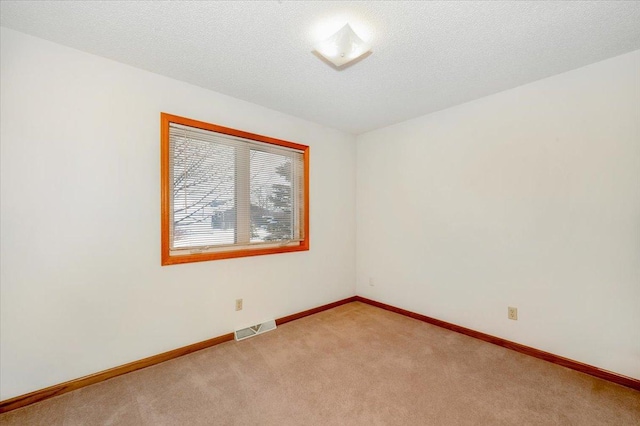 spare room featuring a textured ceiling and light carpet