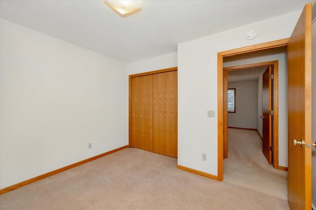 unfurnished bedroom with a textured ceiling, light colored carpet, and a closet