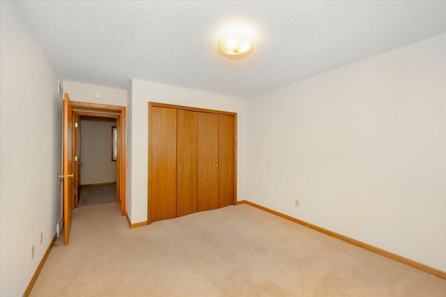 unfurnished bedroom with light colored carpet, a closet, and a textured ceiling