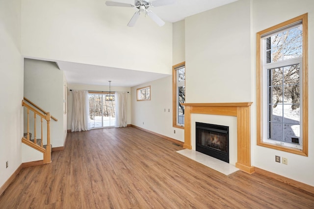 unfurnished living room with ceiling fan with notable chandelier and hardwood / wood-style flooring