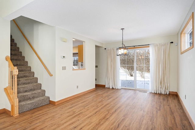 spare room with a notable chandelier and wood-type flooring