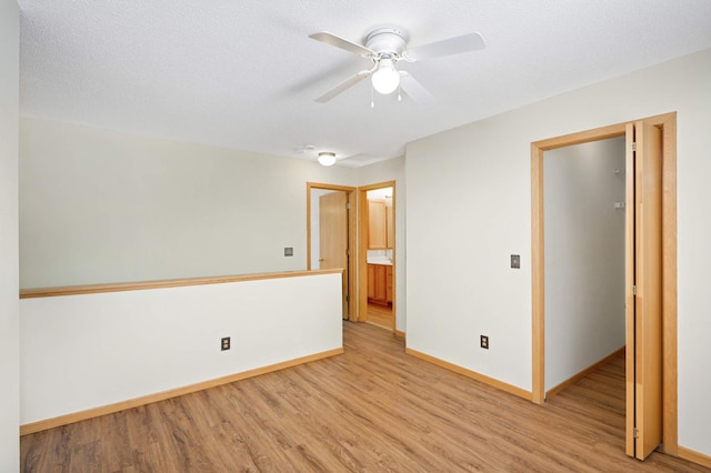 empty room featuring a textured ceiling, ceiling fan, and light hardwood / wood-style flooring