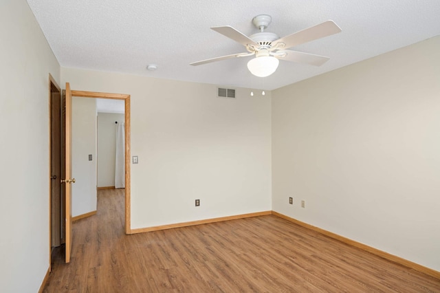 unfurnished room featuring ceiling fan, light wood-type flooring, and a textured ceiling