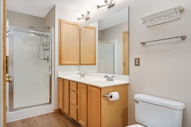 bathroom featuring hardwood / wood-style floors, toilet, vanity, a shower with shower door, and a textured ceiling