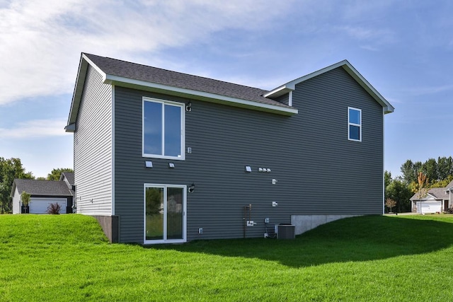 rear view of property with central air condition unit and a lawn