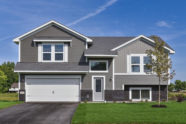 view of front of house featuring board and batten siding, a shingled roof, a front lawn, driveway, and an attached garage