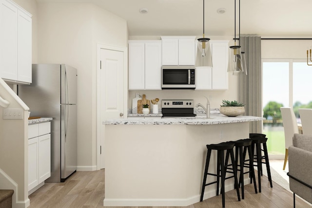 kitchen featuring light wood finished floors, white cabinets, appliances with stainless steel finishes, and a kitchen island with sink