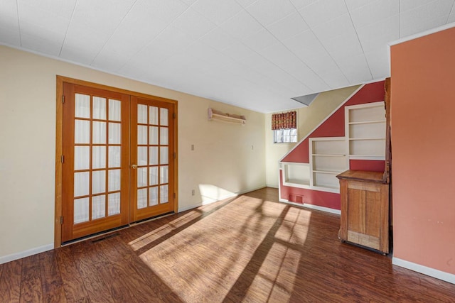 spare room with dark wood-type flooring, built in shelves, french doors, and a wall mounted air conditioner