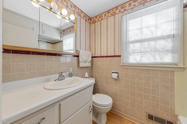 bathroom with toilet, vanity, tile walls, and hardwood / wood-style floors