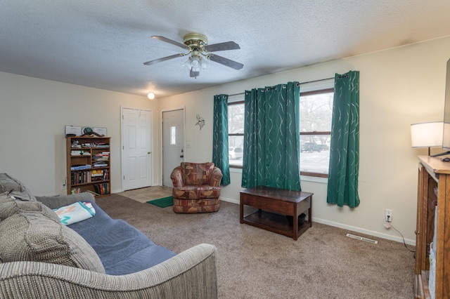 living room featuring ceiling fan, light colored carpet, and a textured ceiling