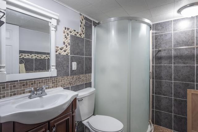 bathroom featuring toilet, a shower with shower door, backsplash, tile walls, and vanity