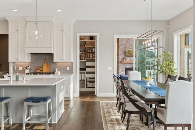 dining area with sink, dark hardwood / wood-style floors, a notable chandelier, and a stone fireplace