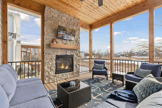 interior space featuring ceiling fan, wood ceiling, plenty of natural light, and an outdoor stone fireplace