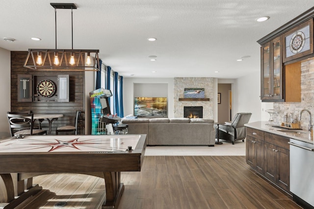 game room featuring wood-type flooring, a fireplace, wet bar, and a textured ceiling