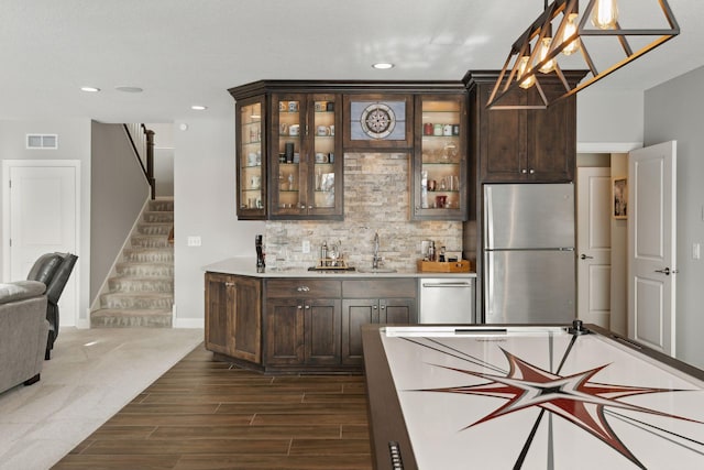 interior space featuring dark brown cabinets, pendant lighting, sink, and stainless steel appliances