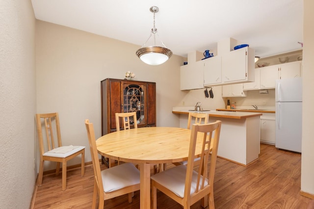 dining space with sink and light hardwood / wood-style flooring