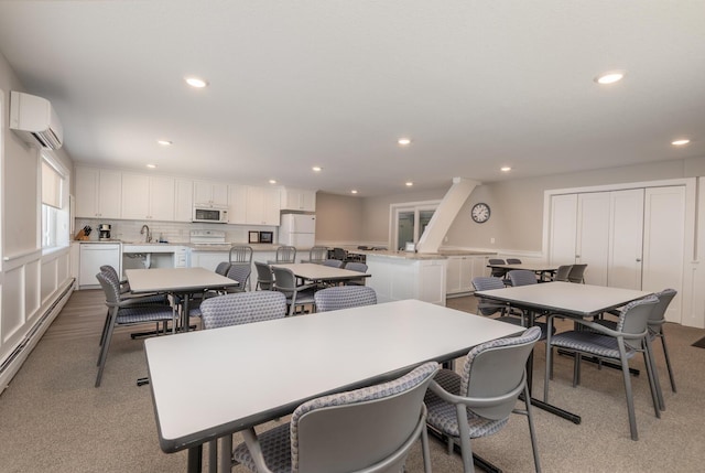 dining space featuring a baseboard heating unit, an AC wall unit, and sink