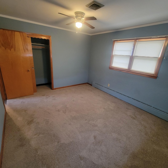 unfurnished bedroom with crown molding, light colored carpet, a closet, ceiling fan, and a baseboard heating unit