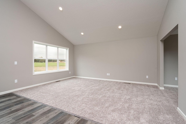 empty room featuring lofted ceiling, a textured ceiling, and hardwood / wood-style floors