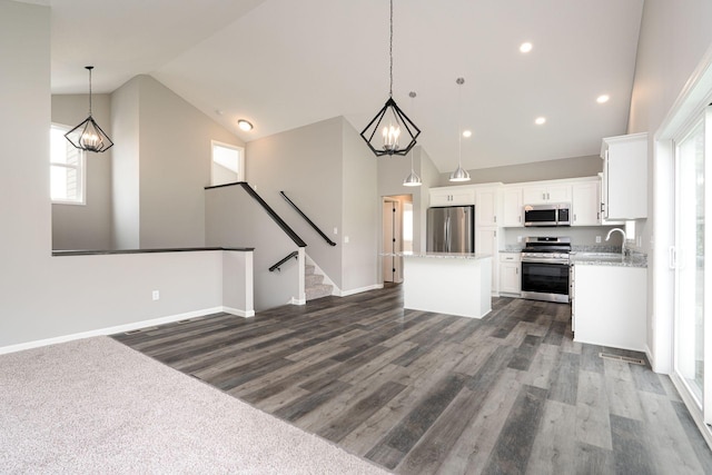 kitchen with decorative light fixtures, a kitchen island, white cabinetry, appliances with stainless steel finishes, and sink