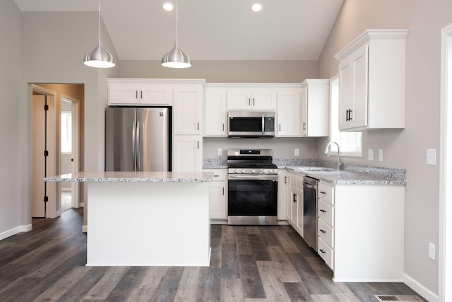 kitchen featuring appliances with stainless steel finishes, hanging light fixtures, white cabinetry, and sink