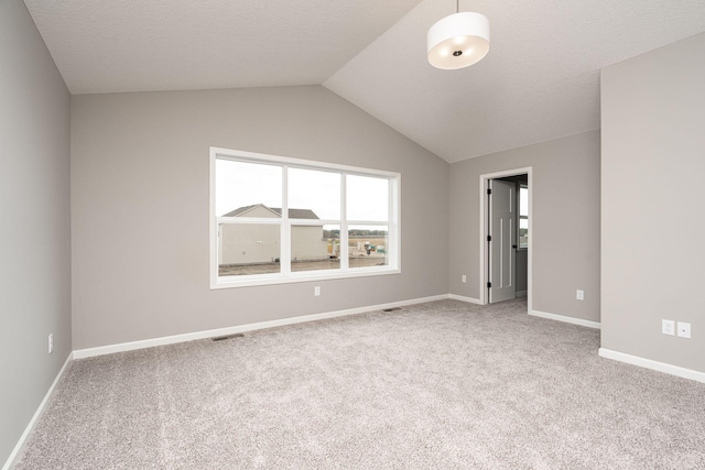 carpeted spare room featuring lofted ceiling and a textured ceiling