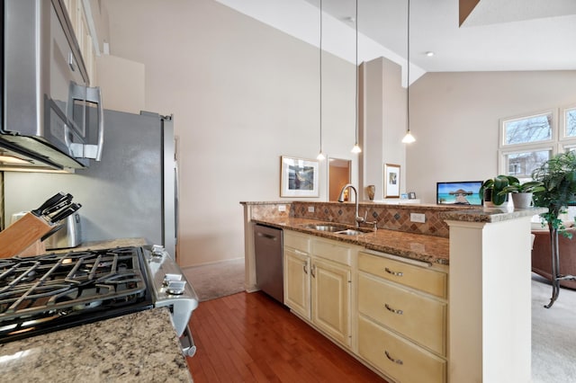 kitchen featuring light stone countertops, cream cabinets, decorative light fixtures, stainless steel appliances, and sink