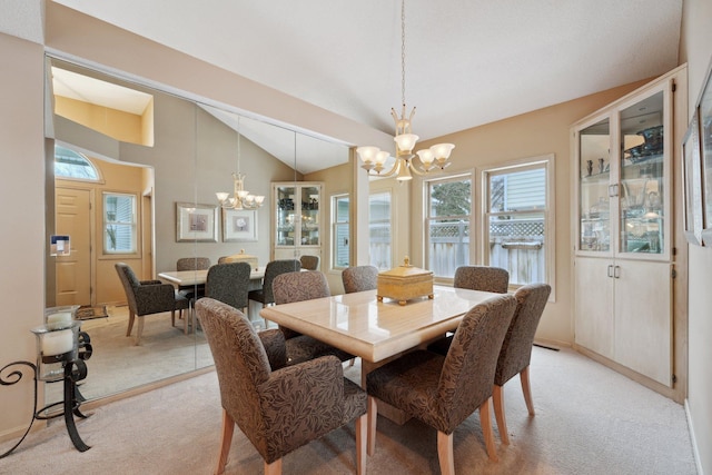 dining area with lofted ceiling, a chandelier, and light colored carpet