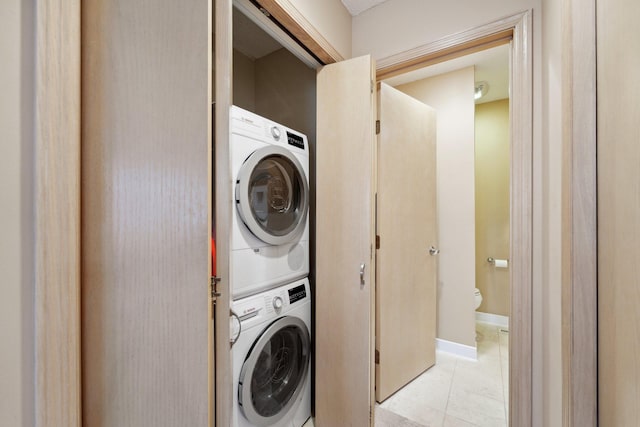 washroom featuring stacked washer and dryer and light tile patterned floors