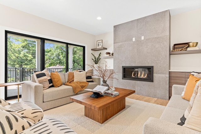 living room featuring light wood-type flooring and a tiled fireplace