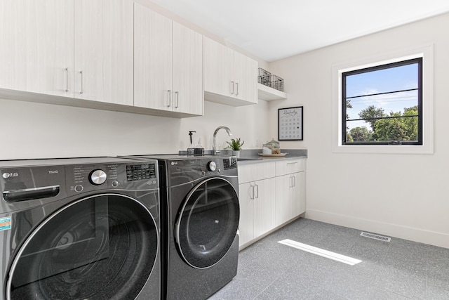 clothes washing area featuring sink, washer and clothes dryer, and cabinets