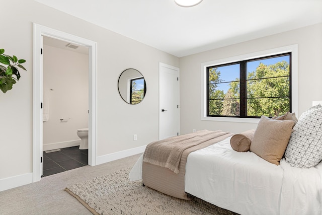 bedroom with dark carpet and connected bathroom