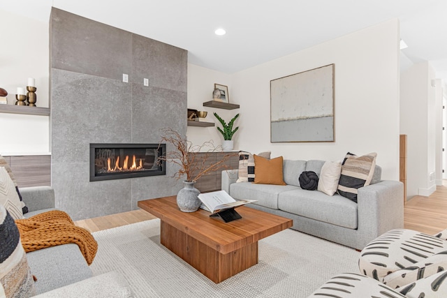 living room with a tile fireplace and light hardwood / wood-style floors