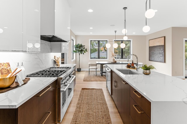 kitchen with an island with sink, sink, hanging light fixtures, and appliances with stainless steel finishes