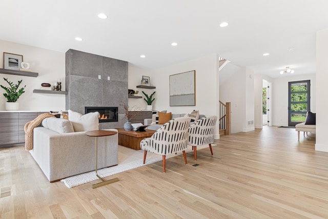 living room featuring a tile fireplace and light wood-type flooring