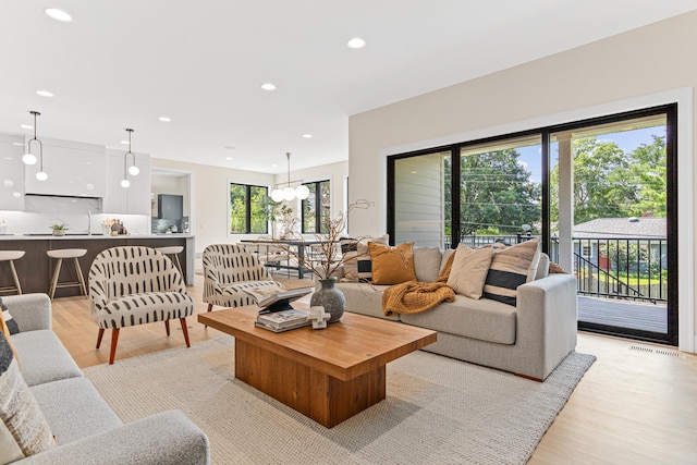 living room featuring light wood-type flooring, a wealth of natural light, and a notable chandelier