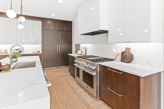 kitchen featuring hanging light fixtures, double oven range, sink, white cabinetry, and backsplash