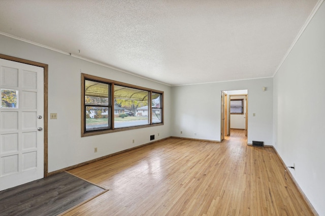 foyer featuring light wood-type flooring, a textured ceiling, and crown molding