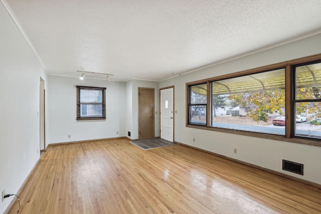 interior space featuring a textured ceiling, crown molding, and light hardwood / wood-style floors