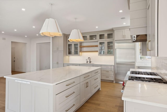 kitchen featuring hanging light fixtures, appliances with stainless steel finishes, light stone counters, and a kitchen island