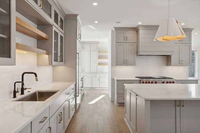 kitchen featuring decorative light fixtures, tasteful backsplash, light hardwood / wood-style floors, sink, and gray cabinetry