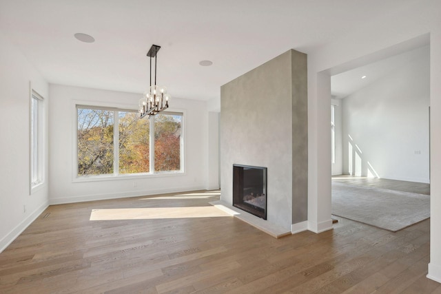 unfurnished living room featuring light wood-type flooring, a fireplace, and a chandelier